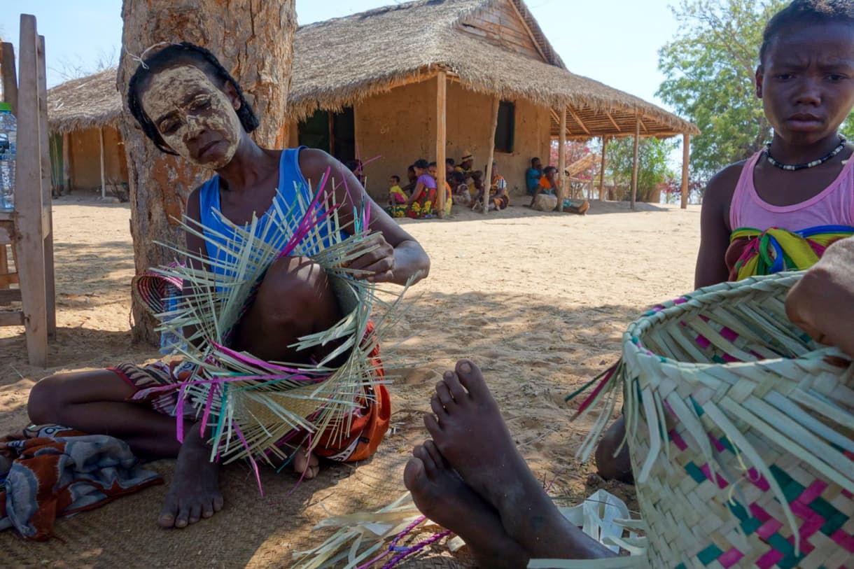 Femmes tressant des paniers en raphia dans un village malgache, ambiance artisanale et communautaire.