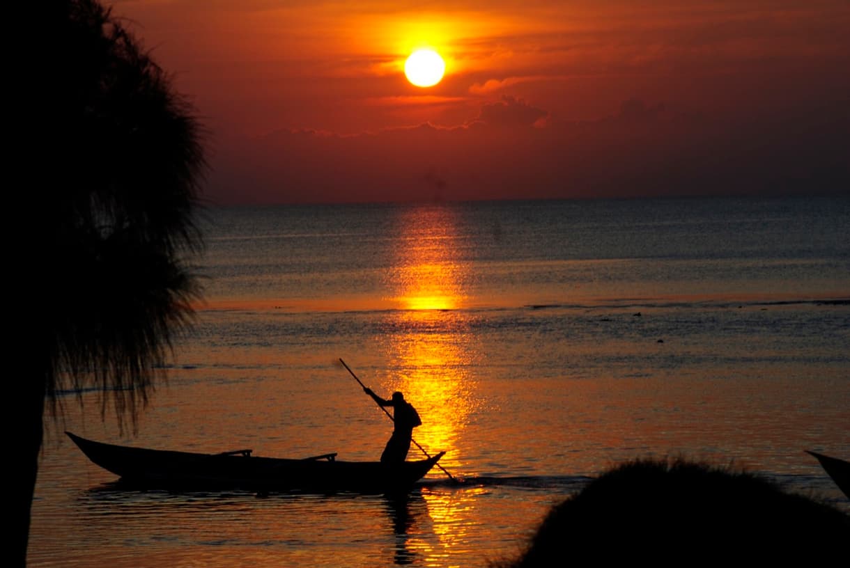 Un homme pagayant sur un bateau au coucher de soleil à Madagascar
