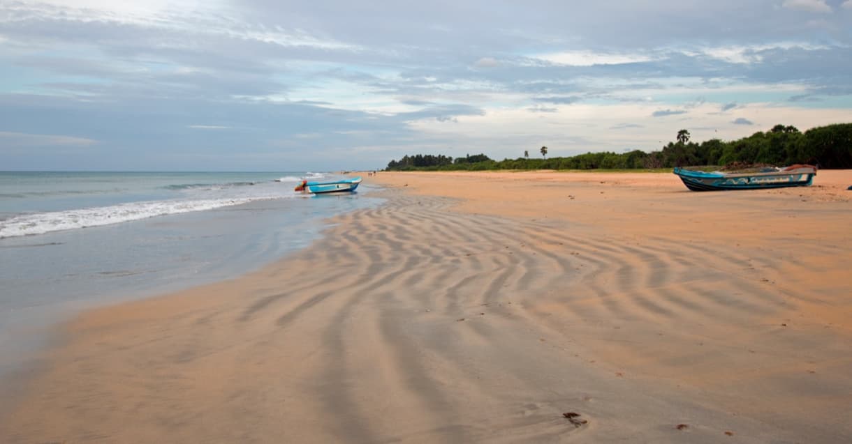 Nilaveli Beach au Sri Lanka, avec des motifs de sable et des bateaux au bord de l'eau