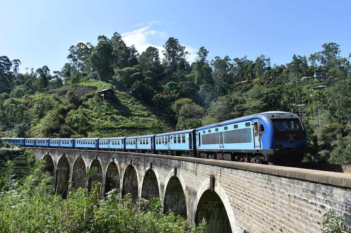 Train bleu traversant un viaduc dans un paysage verdoyant près de Kandy, Sri Lanka.