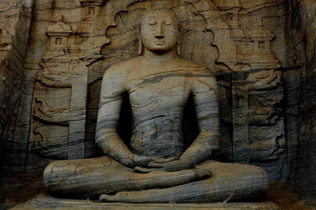 Statue de Bouddha taillée dans la roche avec motifs sculptés en arrière-plan, Sri Lanka