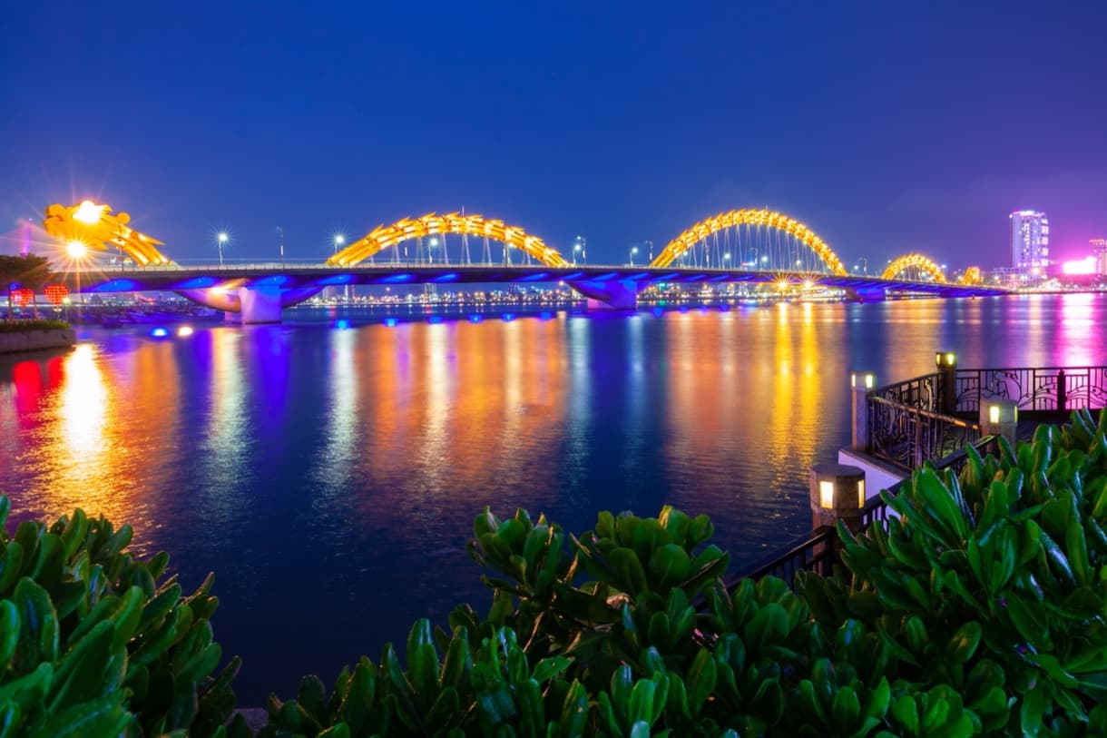 Pont du Dragon illuminé la nuit à Da Nang, reflétant des couleurs vives sur la rivière.