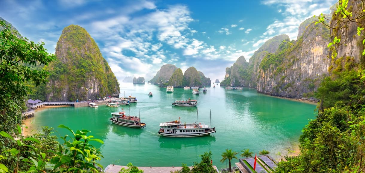 Vue pittoresque de la baie d'Halong avec des formations rocheuses et des bateaux dans une eau turquoise.