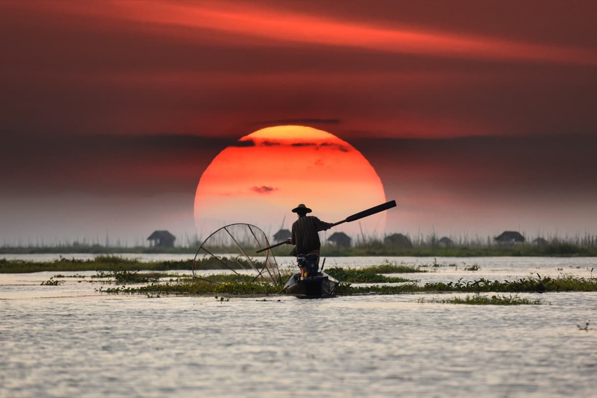 Pêcheur local sur un lac au coucher de soleil, Vietnam