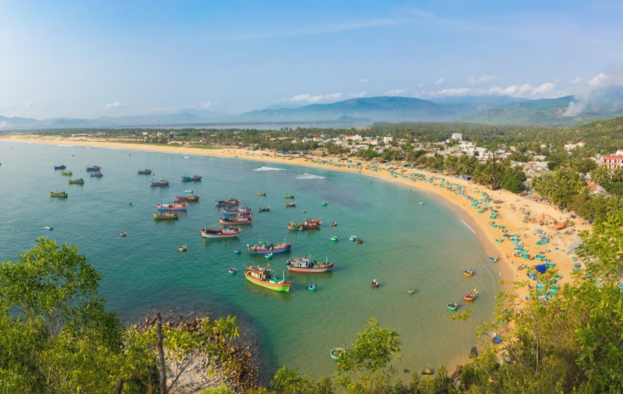 Plage de Quy Nhon avec bateaux colorés et paysage côtier au Vietnam
